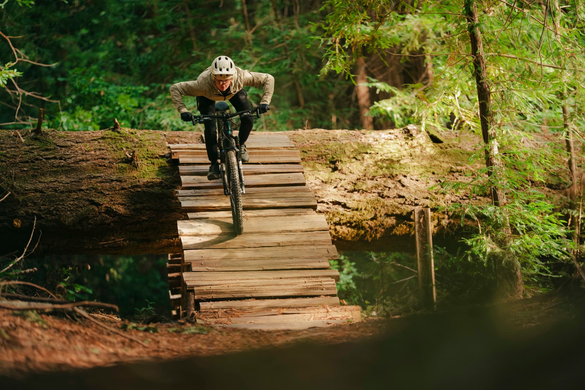 Ciclista descendiendo una rampa de madera sobre una bicicleta eléctrica en un bosque