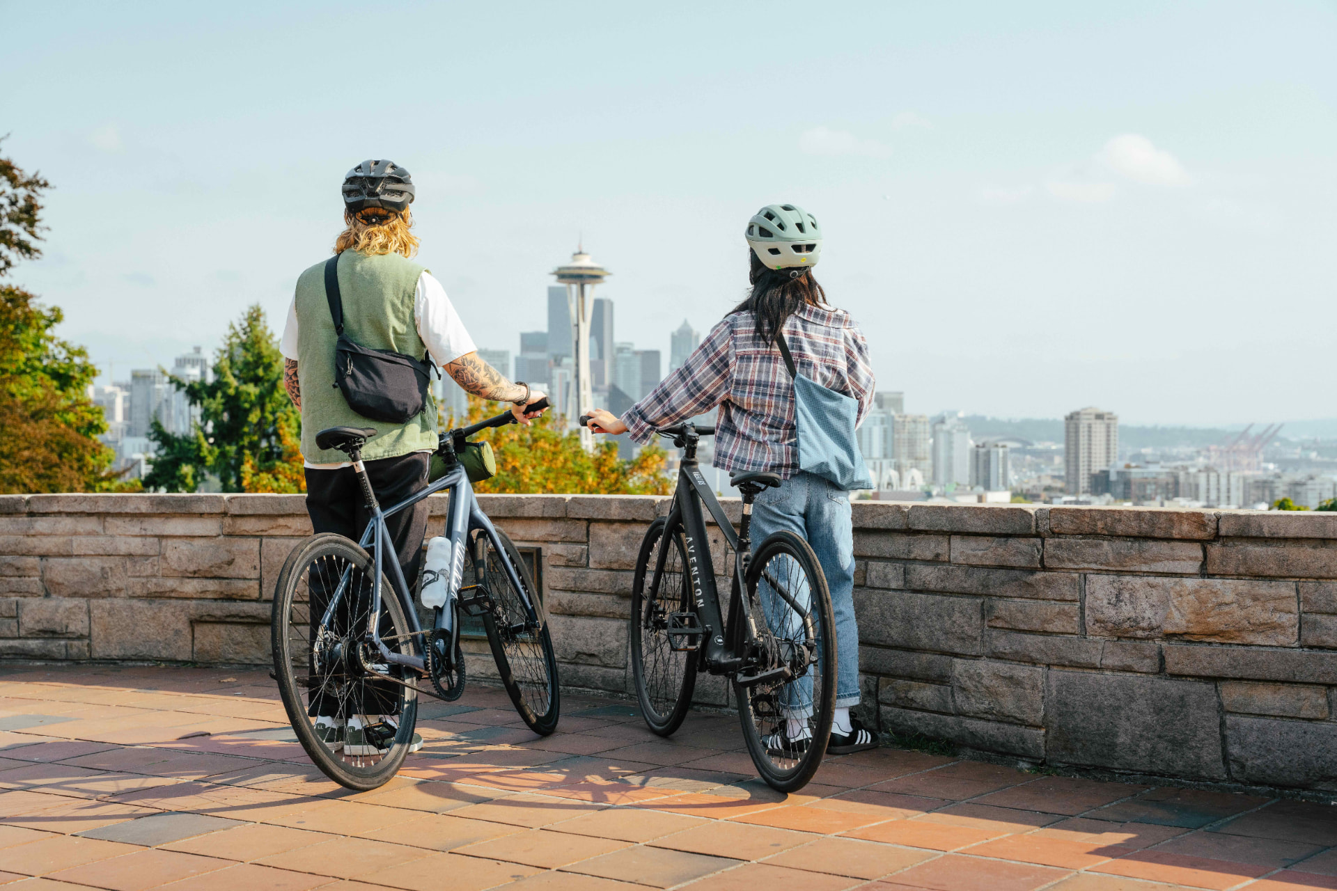 Dos personas con sus bicicletas eléctricas Aventon Soltera frente a la ciudad